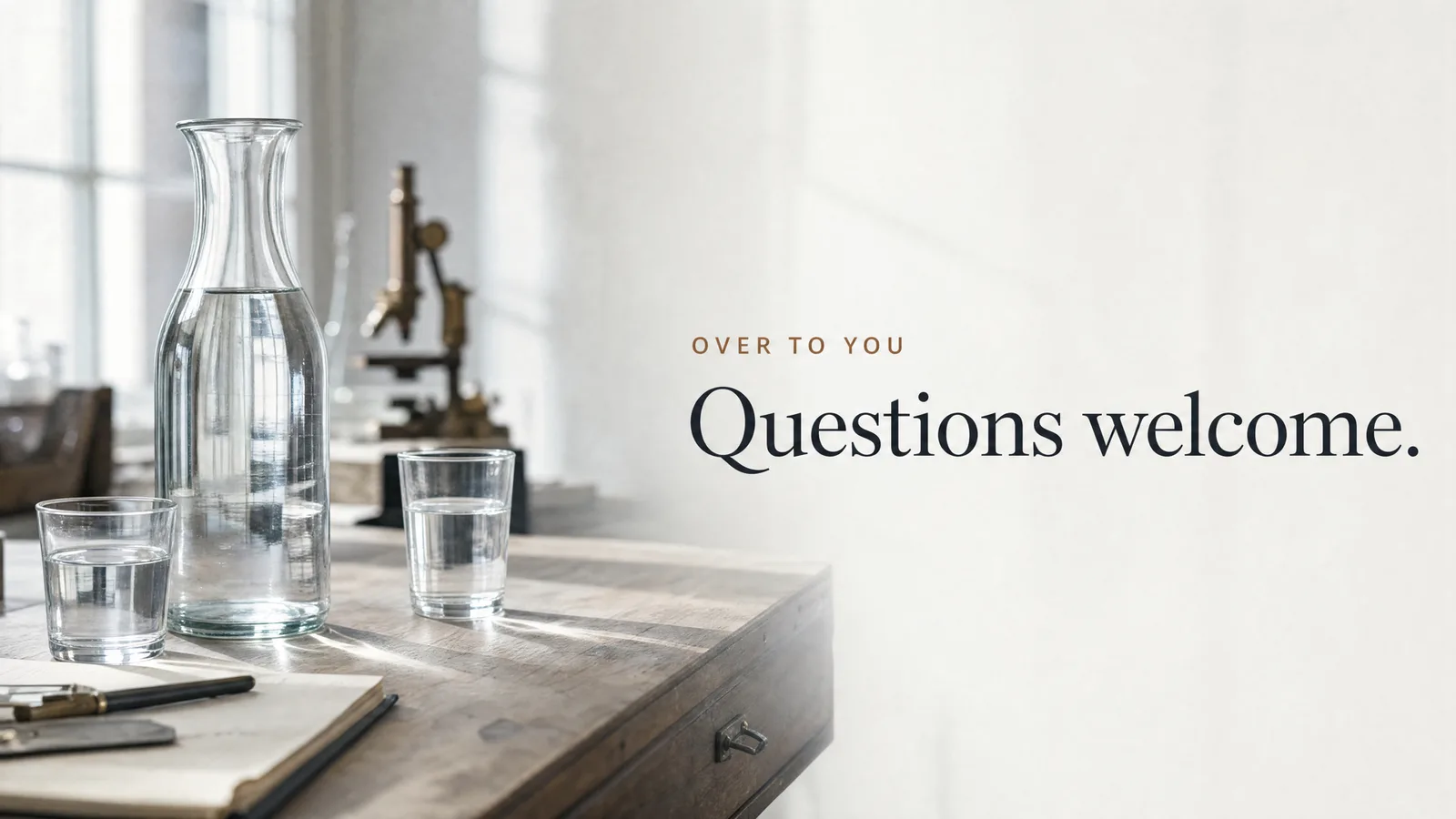 Slide: Over to you — Questions welcome. A glass carafe and two glasses of water beside an open notebook.